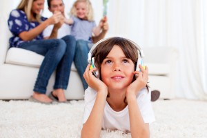 Boy-listening-to-music-with-family-in-background