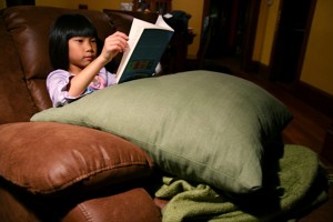little girl reading in large chair