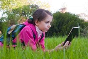 girl reading from an e-reader outside