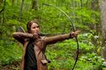 Katniss from Hunger Games with a bow in the woods