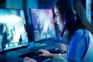 Adolescent female staring intently at a computer screen, playing an MMO in an Esports environment