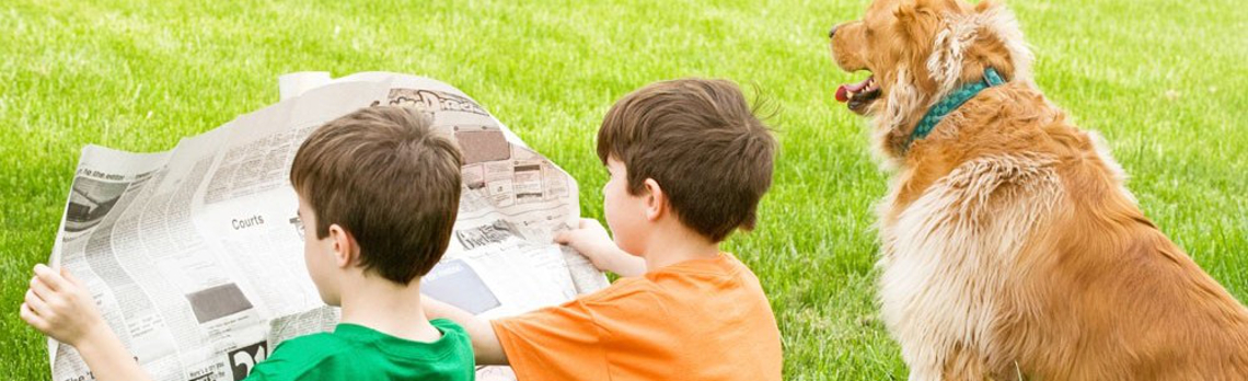 Two boys reading a newspaper outside