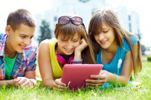 children viewing a tablet on grass