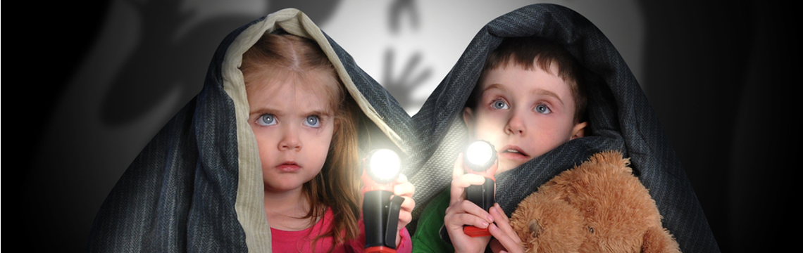 two kids with flashlight under covers