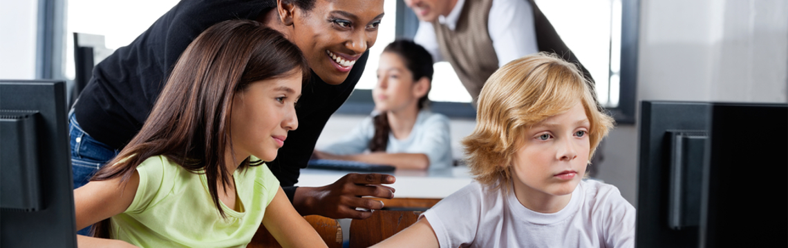 teacher helping two students with a computer