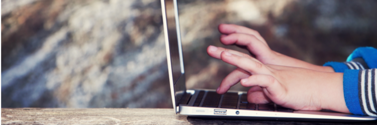 Child's hands typing on a laptop