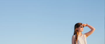 Young woman standing againt a blue sky looking into the distance