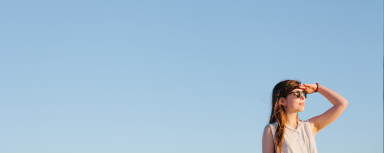 Young woman standing againt a blue sky looking into the distance