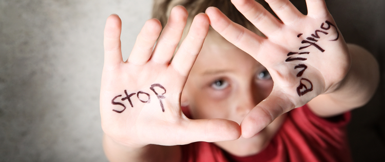 Young boy showing his hands, with the words 'stop bulling' painted on them
