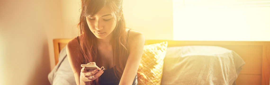 Young woman on her smartphone in golden sunlight