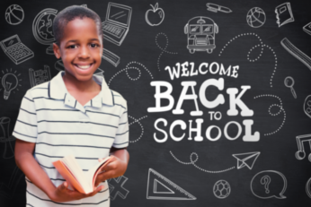School aged boy holding a book in front of a chalkboard
