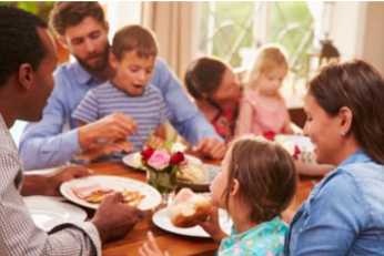 Various parents and children eating a meal around the same table.