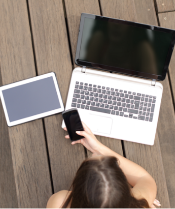 Teen girl using a cell phone, laptop, and tablet