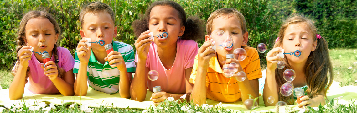 Children laying on the grass blowing bubbles