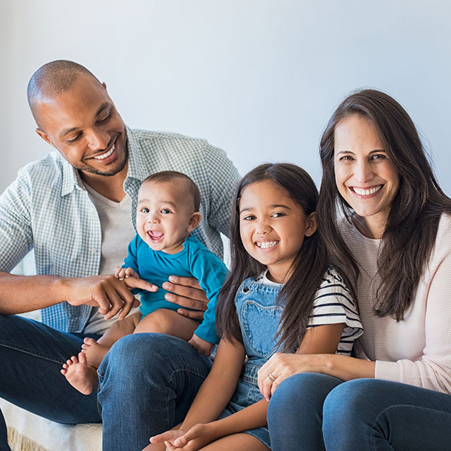 family of four smiling on a couch