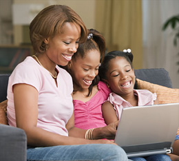 Mother and daughters smiling at laptop
