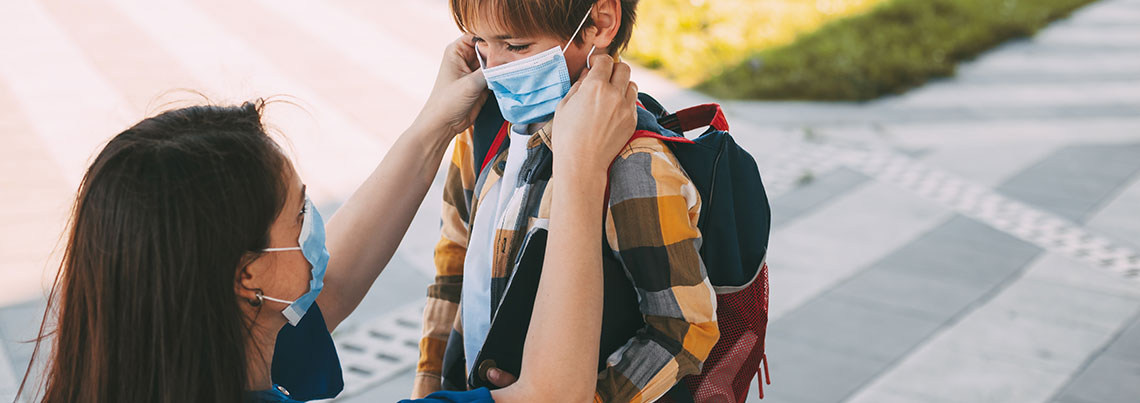 parent putting a mask on child for school